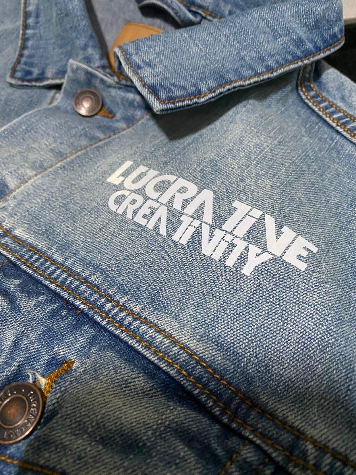 Close-up of a Lucrative Creativity graphic printed on a denim jacket