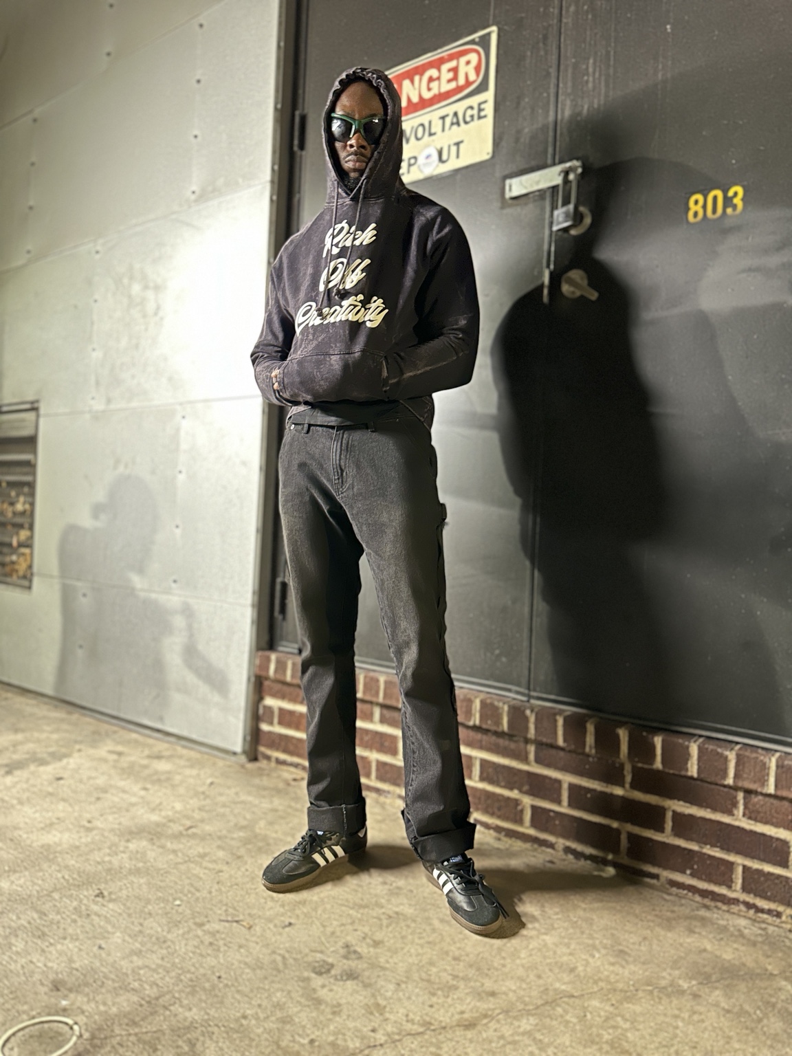 Man wearing the washed black Rich Off Creativity hoodie in an industrial setting