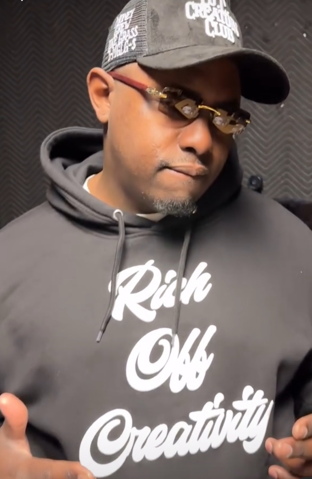Male creative wearing a black Rich Off Creativity hoodie and Creators Club cap